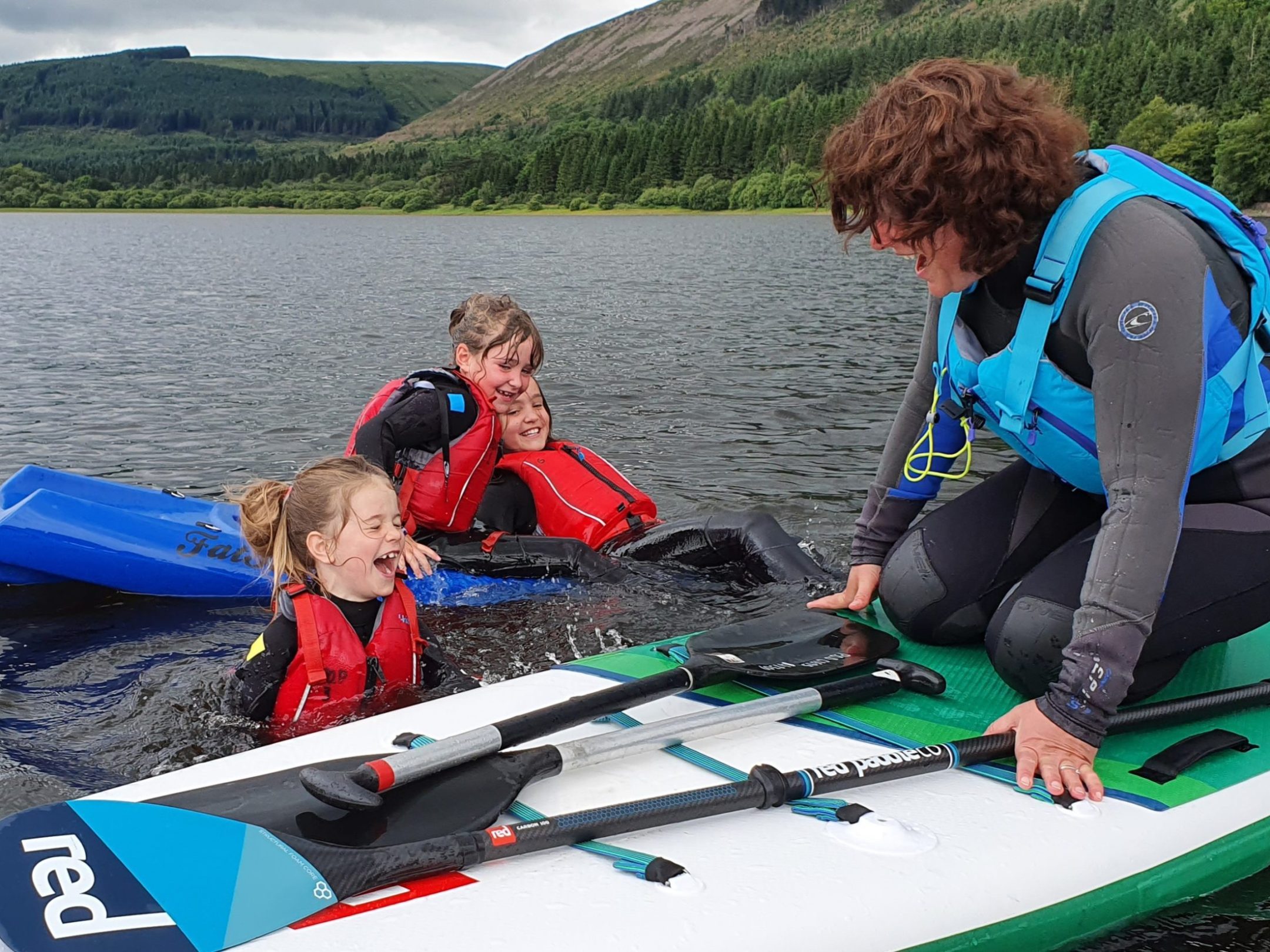 a group of young men sitting next to a body of water