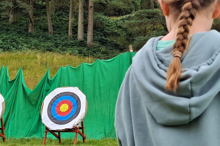 a person holding a kite while standing in the grass