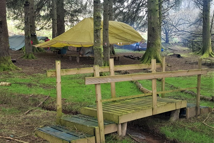 a couple of lawn chairs sitting on top of a grass covered field