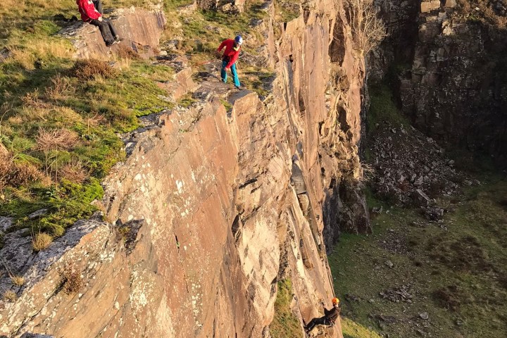 a person flying a kite on the side of a mountain