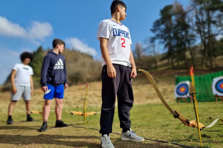 a young boy holding a football ball on a field