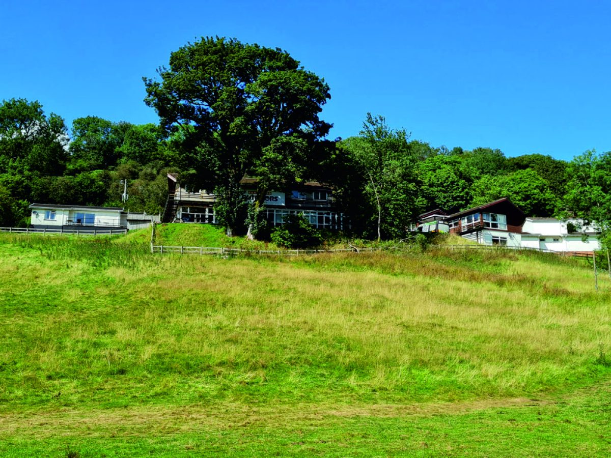 A field with accommodations in the background at Parkwood Outdoors Dolygaer