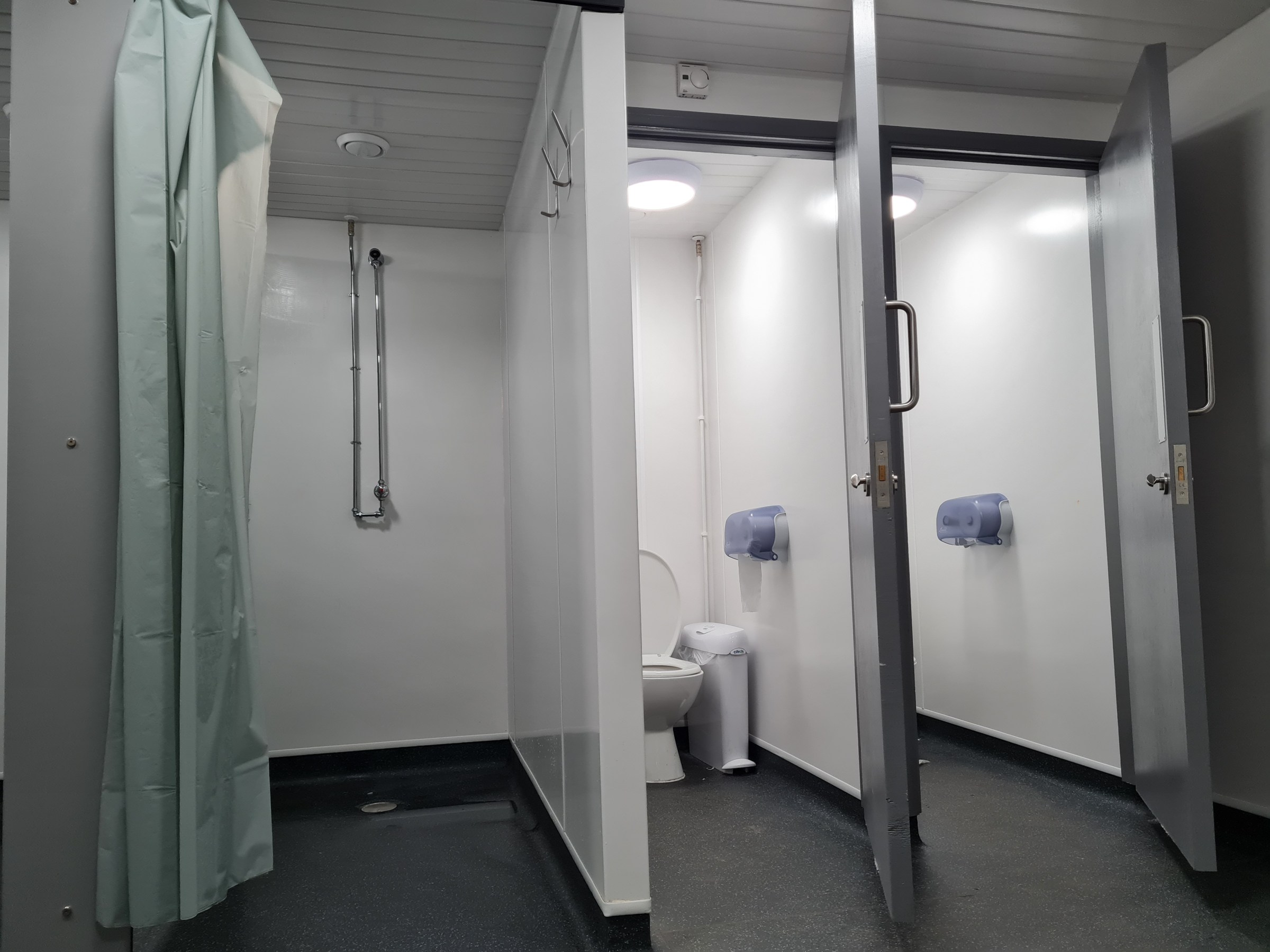 Public restroom with stalls, a shower, and toilet.