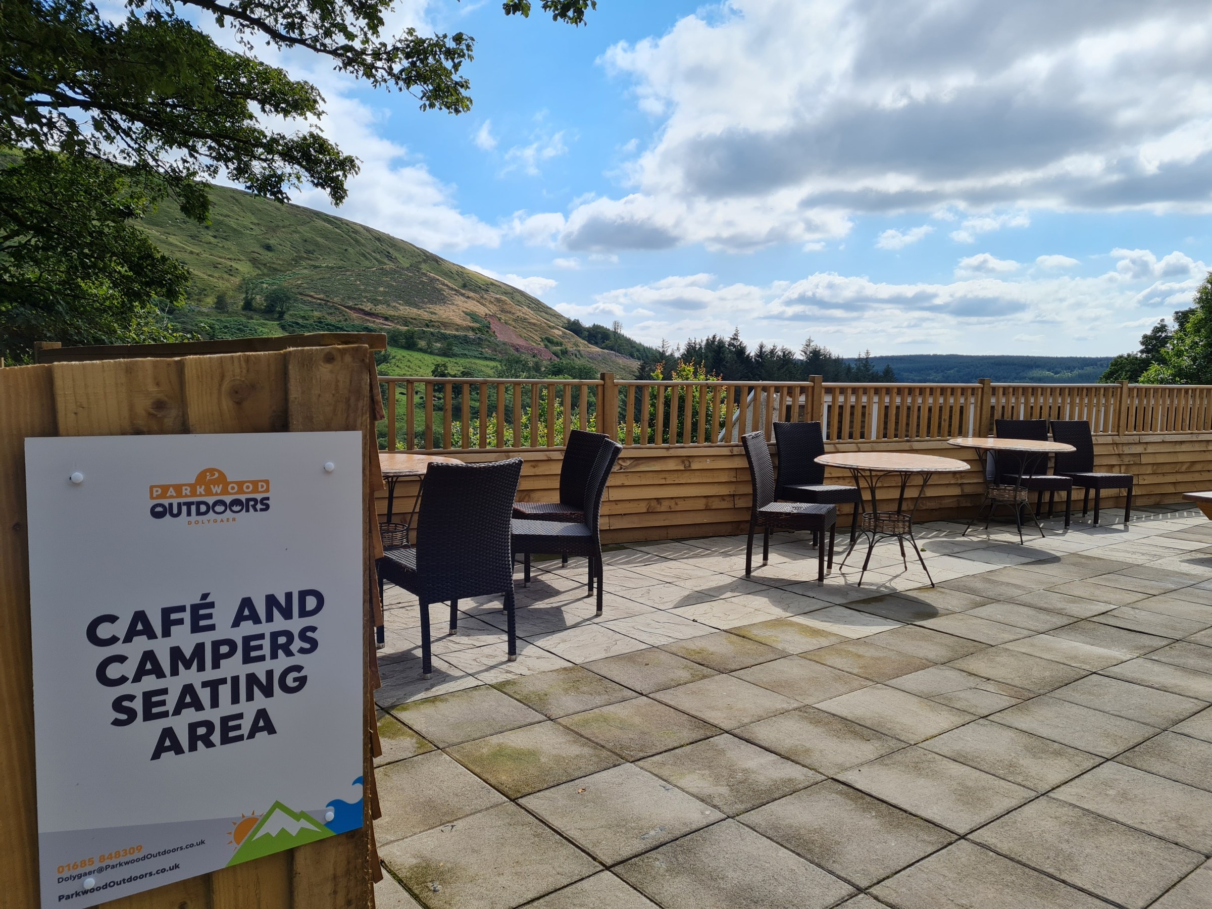 Outdoor café seating with mountain view under a partly cloudy sky.