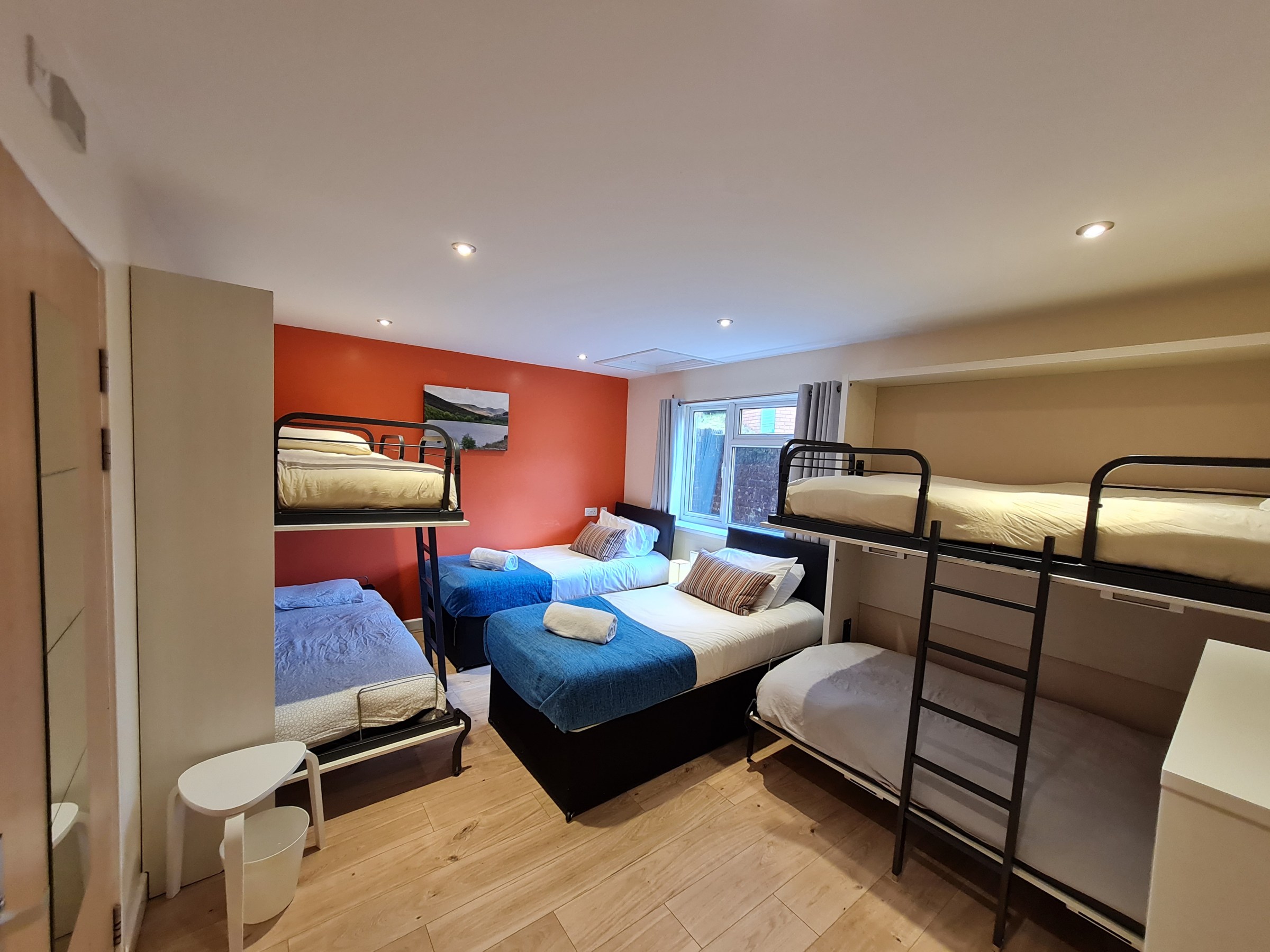 Room with bunk beds, single beds, and red accent wall.