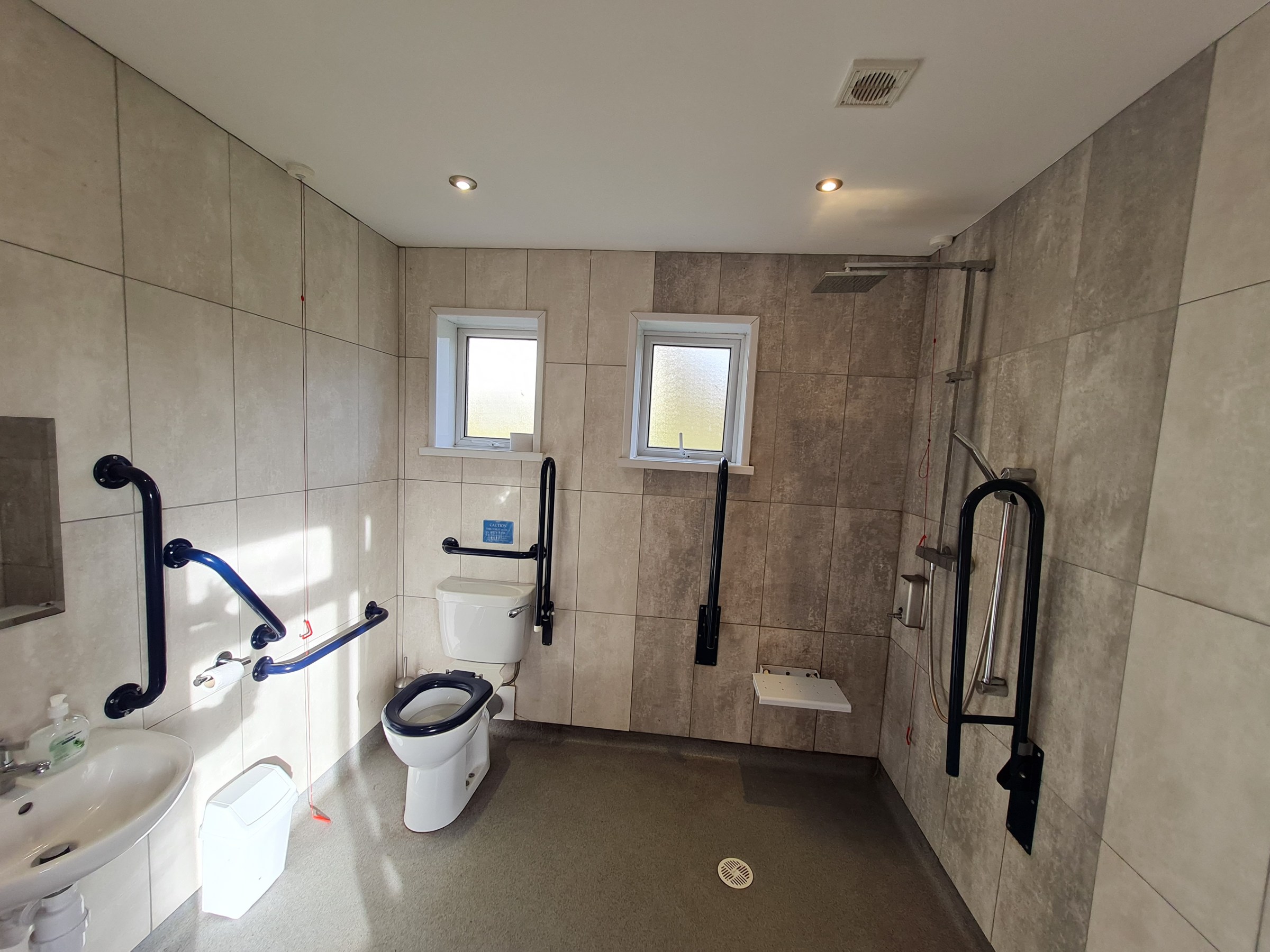 Accessible bathroom with wide space, handrails, and shower area.