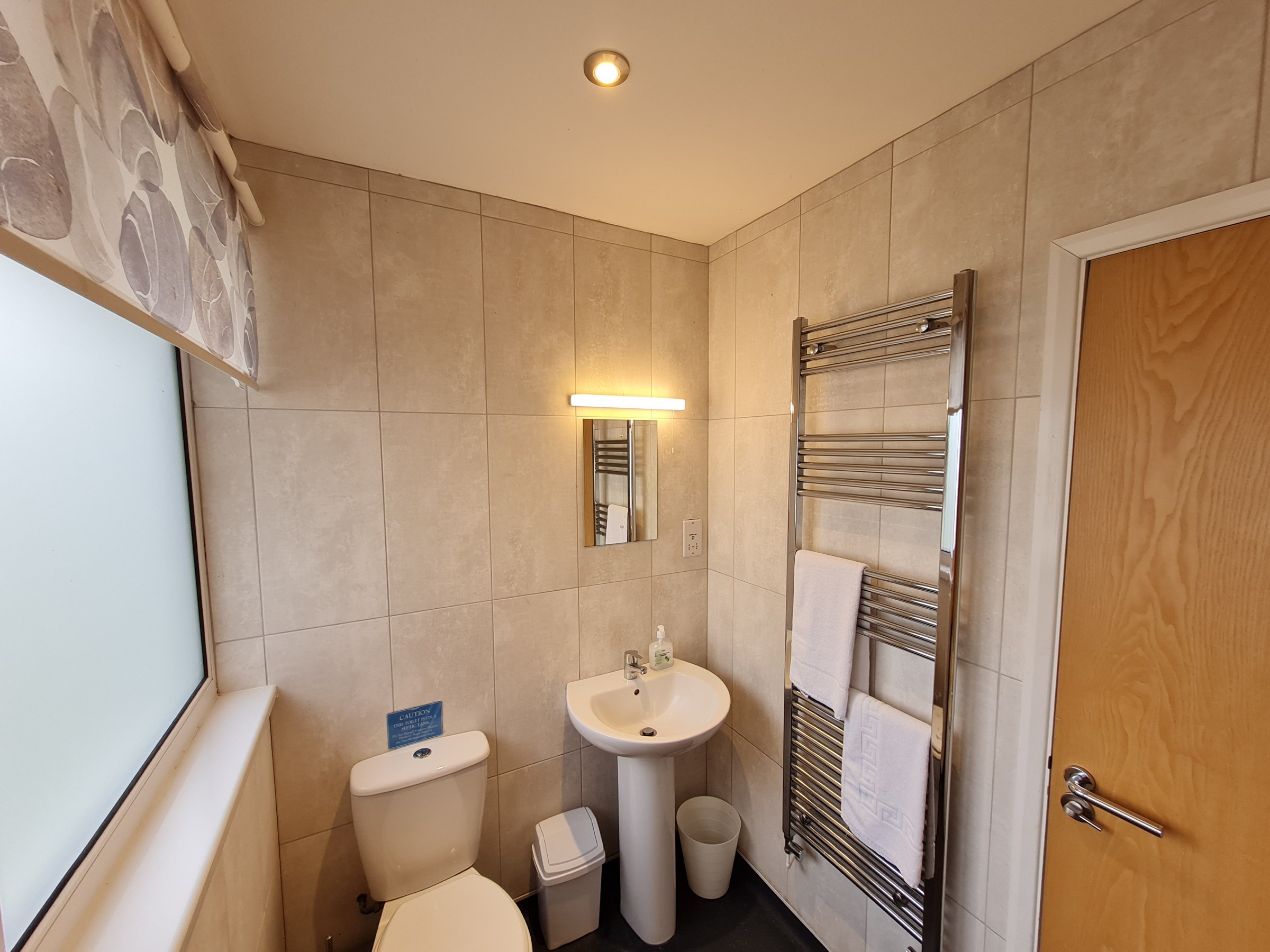 Small bathroom with toilet, sink, towel rail, and mirror.