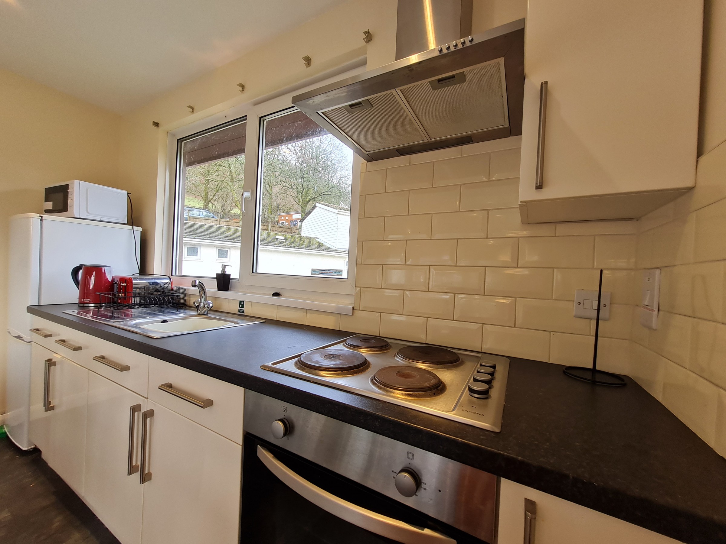 Modern kitchen with stove, oven, refrigerator, and window.