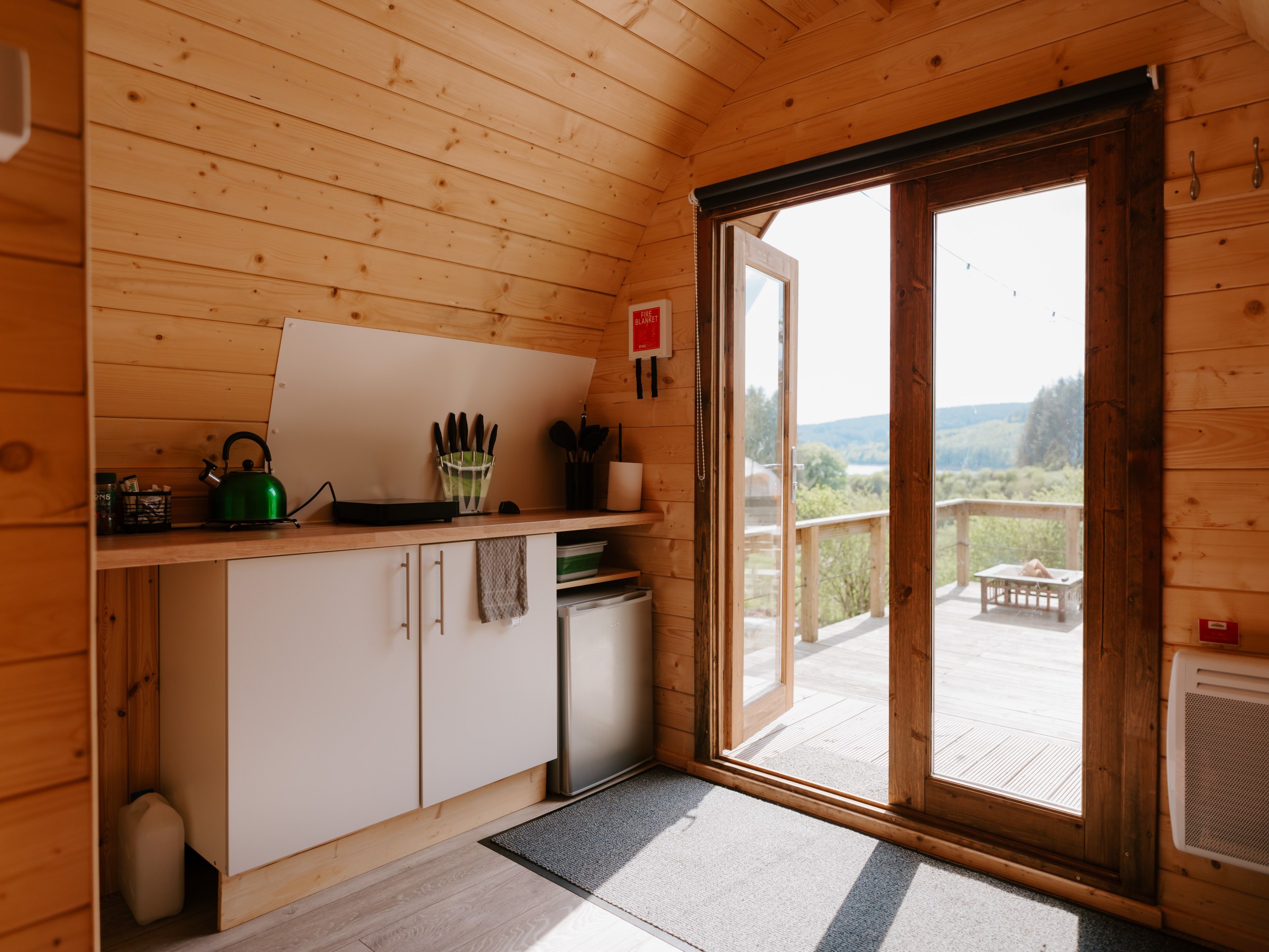 Cozy wooden cabin interior with kitchenette and patio view.