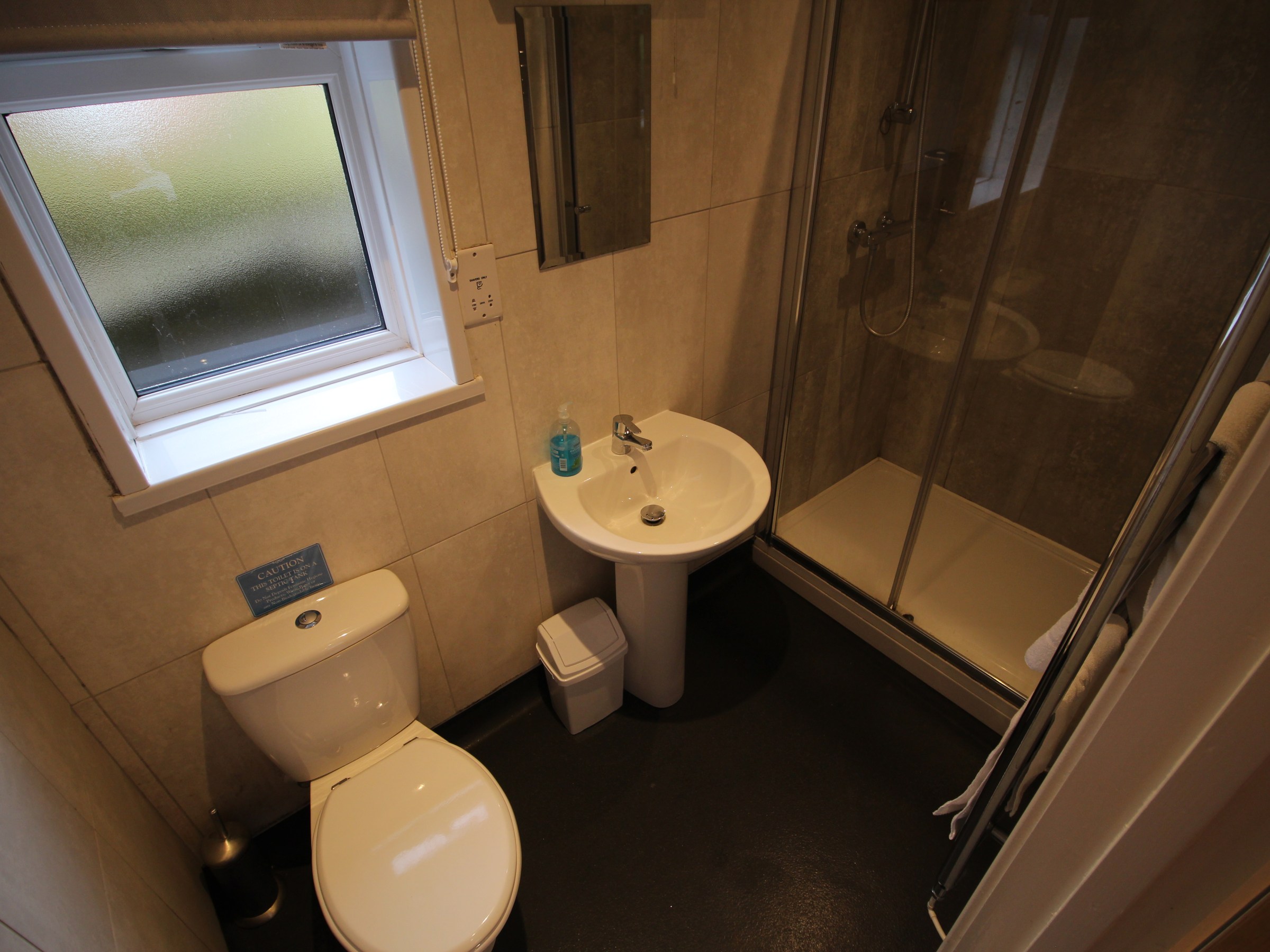 Small bathroom with toilet, sink, and glass shower enclosure.