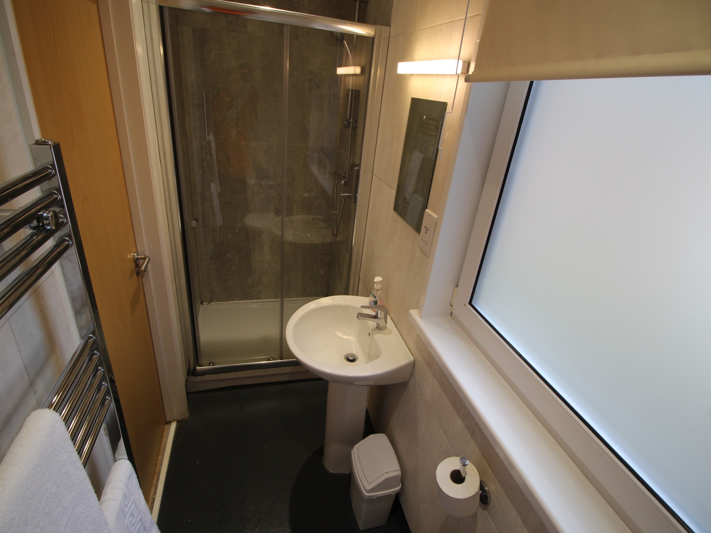 Small bathroom with shower, sink, and towel rack.